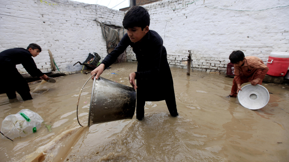 Jóvenes achicando agua tras las lluvias torrenciales de Pakistán