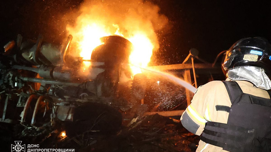 Un bombero tratando de extinguir el fuego en camiones luego de un ataque con misiles en Dnipro, en medio de la invasión rusa de Ucrania