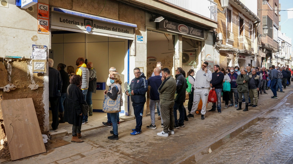 Varias personas hacen cola para comprar Lotería de Navidad en Paiporta