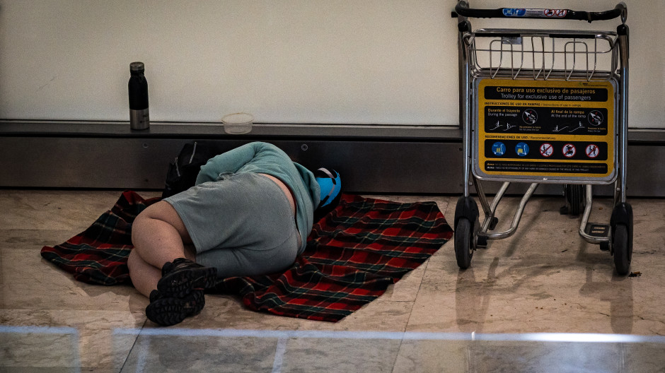 Una persona duerme en la T4 del Aeropuerto Adolfo Suárez-Madrid Barajas