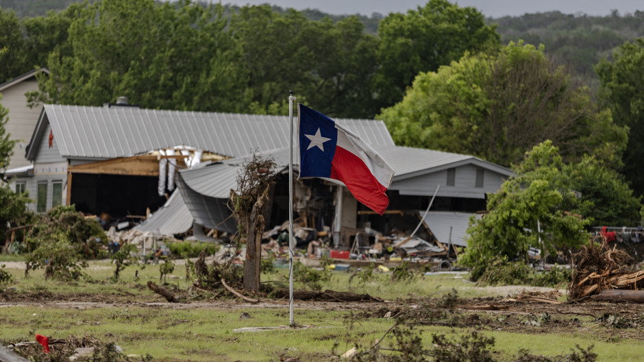 Una bandera de Texas ondea en un patio lleno de escombros