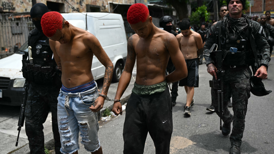 Agentes de policía escoltan a sospechosos en el complejo Penha, en Río de Janeiro, Brasil