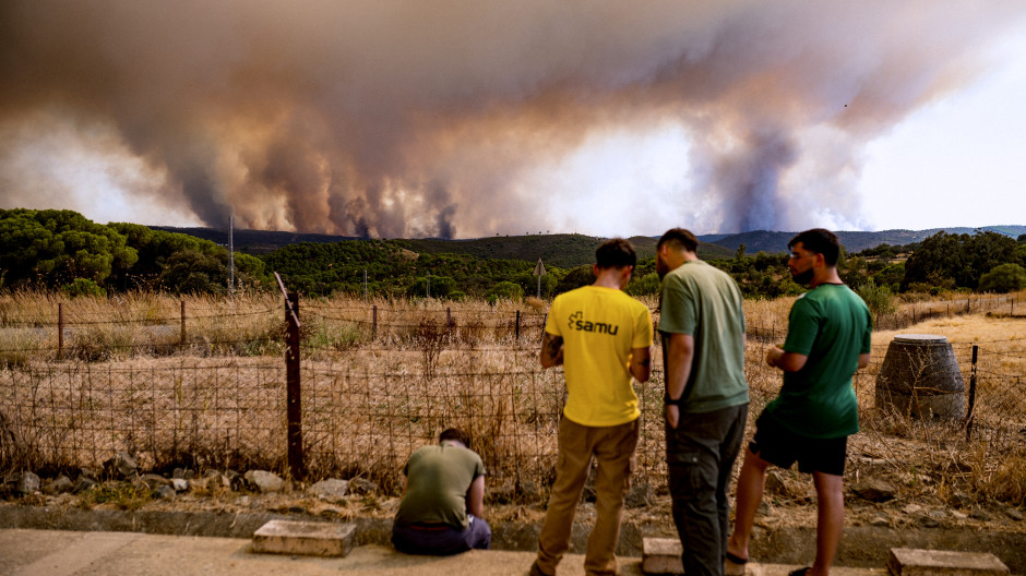 Vecinos de El Madroño, en Sevilla, observan este domingoo el fuego del incendio de Niebla (Huelva),
