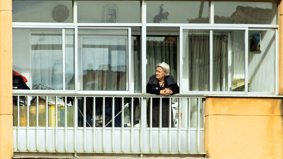 Mujer mayor en el balcón de su casa