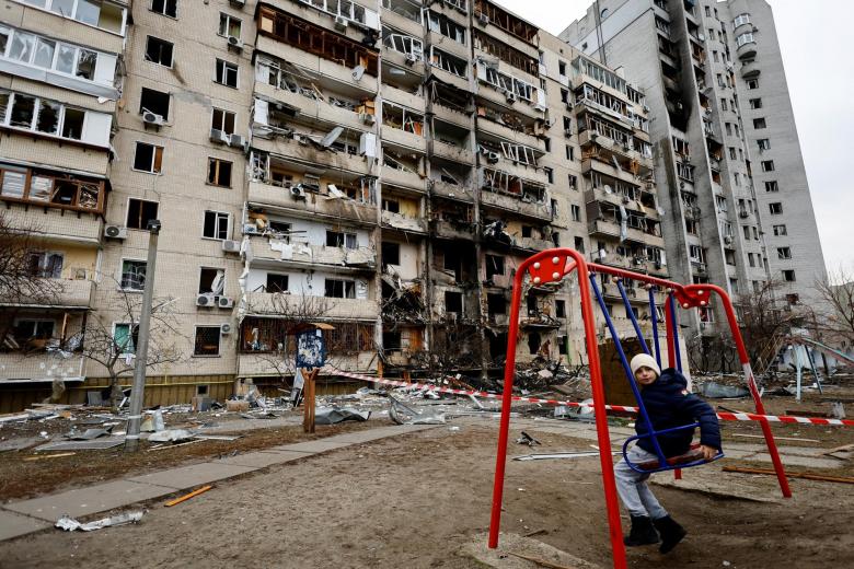 Un niño sentado en un columpio en el exterior de un edificio de viviendas bombardeado en Kiev