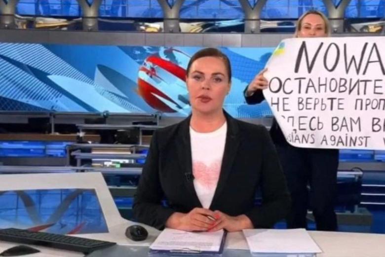 This video grab taken on March 15, 2022 shows Russian Channel One editor Marina Ovsyannikova holds a poster reading " Stop the war. Don't believe the propaganda. Here they are lying to you"  during on-air TV studio by news anchor Yekaterina Andreyeva , Russia's most-watched evening news broadcast, in Moscow on March 14, 2022 . - As a news anchor Yekaterina Andreyeva launched into an item about relations with Belarus, Marina Ovsyannikova, who wore a dark formal suit, burst into view, holding up a hand-written poster saying "No War" in English. (Photo by Handout / AFP) / RESTRICTED TO EDITORIAL USE - MANDATORY CREDIT "AFP PHOTO / Channnel One  - NO MARKETING NO ADVERTISING CAMPAIGNS - DISTRIBUTED AS A SERVICE TO CLIENTS