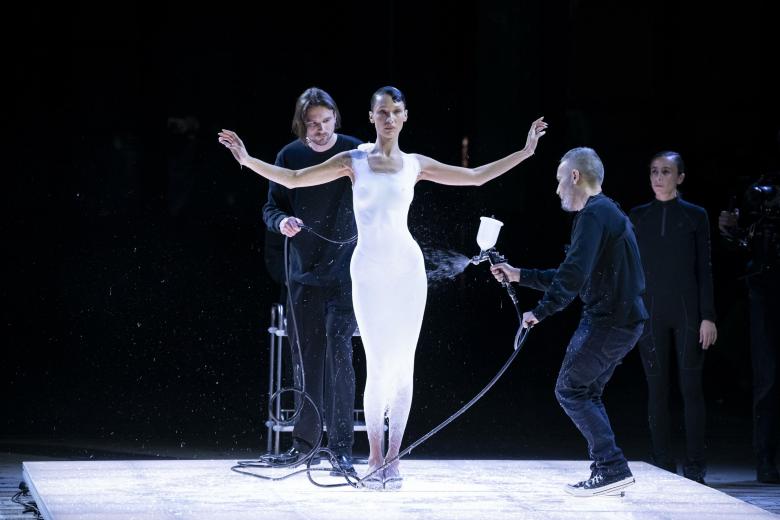 Dos diseñadores de la firma Copernico "tejen" con sprays un vestido blanco sobre Bella Hadid