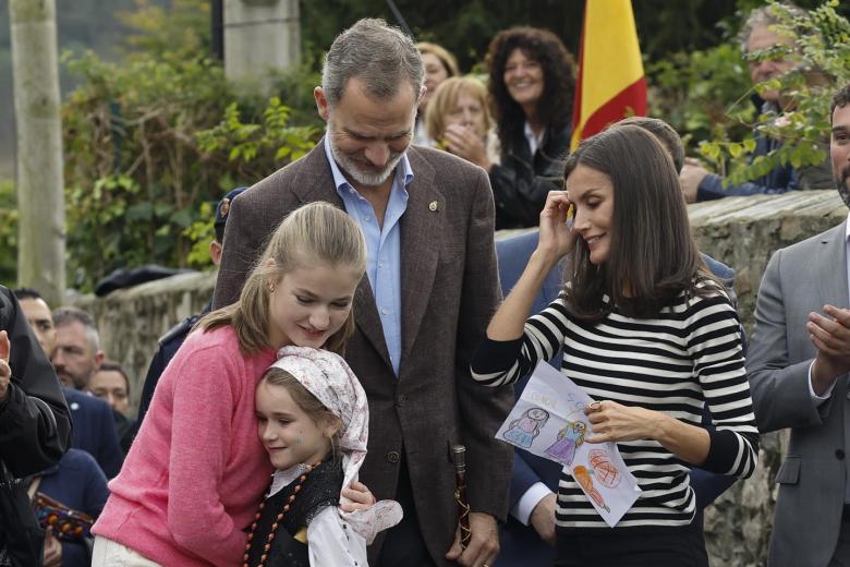 La Princesa de Asturias Leonor (i) abraza a una pequeña en presencia de los Reyes Felipe VI y Letizia durante su visita a la parroquia de Cadavedo