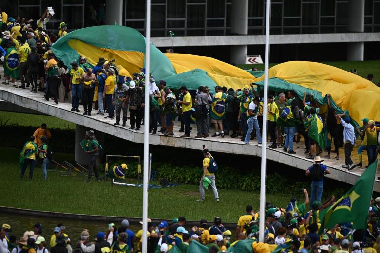 Manifestantes portan una gran bandera de Brasil en su asalto al Congreso