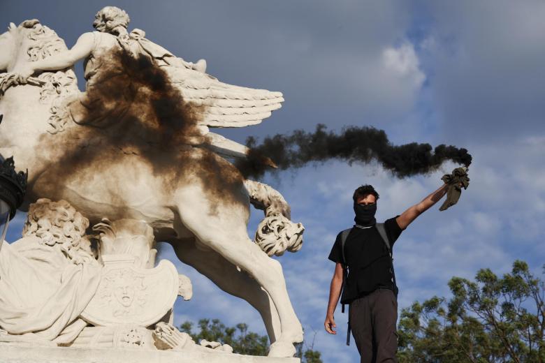 Un manifestante sostiene una bengala de humo durante una protesta en memoria de Nahel