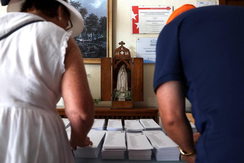 La gente recoge papeletas para votar el día de las elecciones generales anticipadas en un colegio electoral.