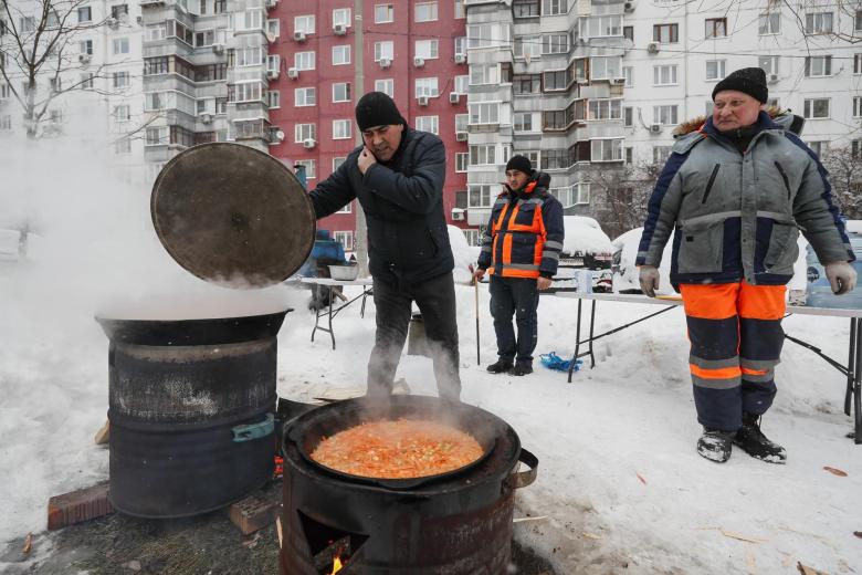 Los trabajadores municipales cocinan durante su descanso para limpiar las calles de nieve en Moscú