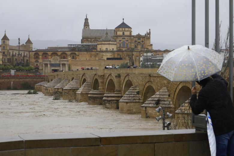Una persona guarecida bajo un paraguas observa la crecida del río Guadalquivir, este domingo en Córdoba. Con mal tiempo comenzó y con mal tiempo se despide: la Semana Santa de 2024 ha estado marcada por la lluvia, el viento y la nieve en zonas altas a consecuencia de la borrasca Nelson, que este domingo va suavizando sus efectos, con menos incidencias que en días anteriores.