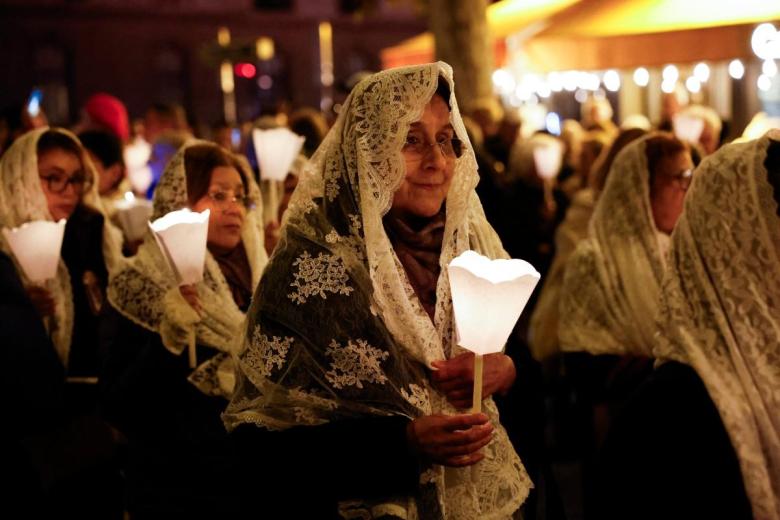 Los fieles sostienen velas durante la procesión de la Virgen María que regresa hacia la Catedral de Notre-Dame