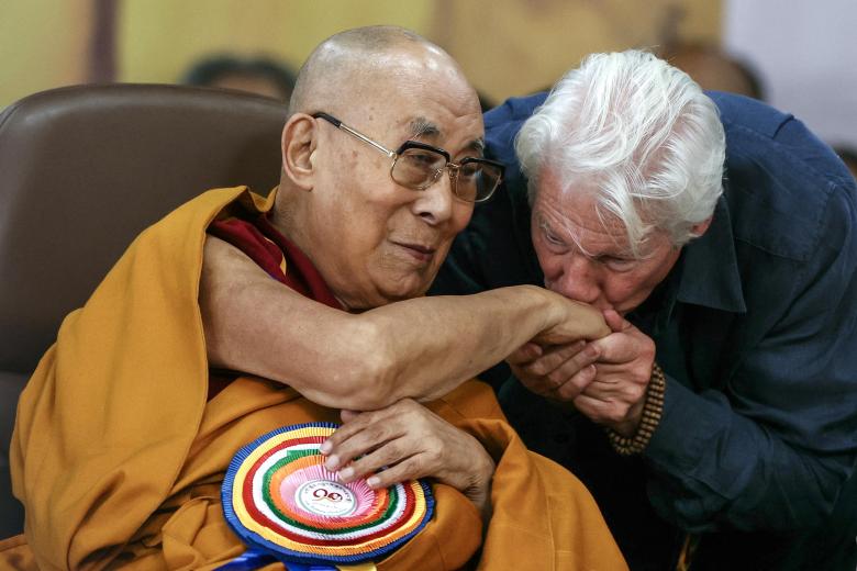 US actor Richard Gere (R) kisses Tibetan spiritual leader the Dalai Lama's hand during a prayer ceremony celebrating his 90th birthday at the Main Tibetan Temple in McLeod Ganj, near Dharamsala, on July 6, 2025. Calling himself a "simple Buddhist monk" who usually didn't celebrate birthdays, the Dalai Lama marked his 90th on July 6 by praying for peace after China insisted it would have the final say on who succeeded the Tibetan spiritual leader. (Photo by Niharika KULKARNI / AFP)