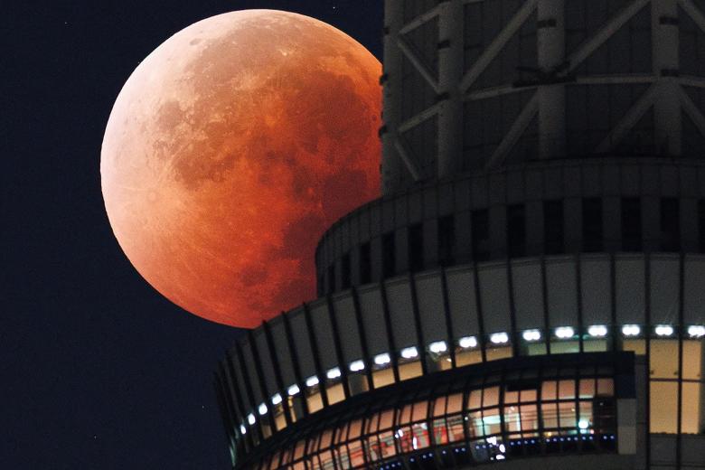 La Luna aparece tras la Torre del Cielo de Tokio durante un eclipse lunar total en plena noche sobre la capital japonesa