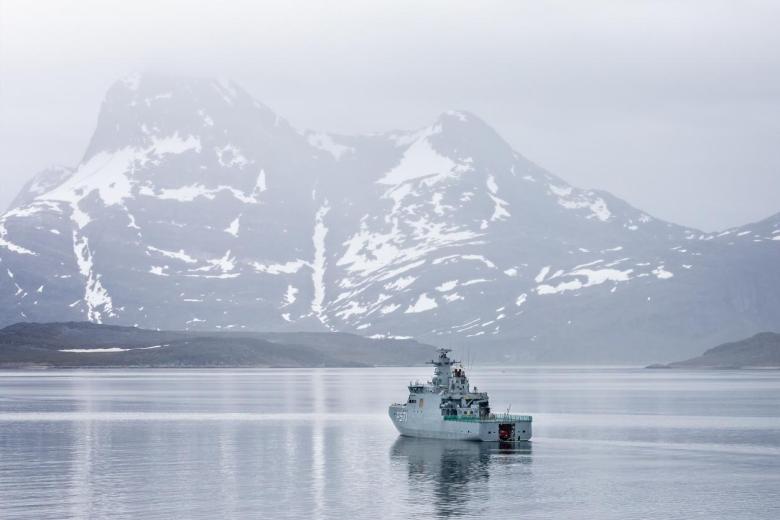 El buque patrullero de la Armada danesa HDMS Ejnar Mikkelsen rodeado de montañas cubiertas de nieve en la entrada de mar que conduce a Nuuk, Groenlandia
