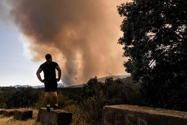 Un hombre contempla la columna de humo provocada por el incendio