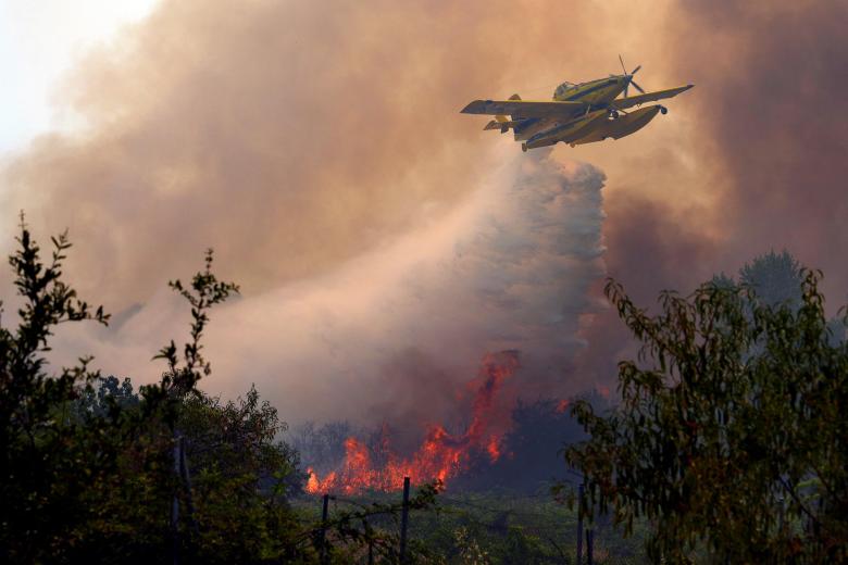 An Air Tractor AT-802F Fire Boss aircraft dumps water over a wildfire burning near San Martin de Valdeiglesias, about 70km west of Madrid, on July 26, 2026. Spanish firefighters today battled a new front of fires near the coastal city of Valencia, where at least 15,000 people were evacuated. In the western Madrid region, two separate wildfires merged on July 24 into a massive blaze that nearly joined another fire in neighboring Castile and Leon. The flames have already burned 25,000 hectares across Madrid and neighboring Avila province, forcing more than 60,000 people (a downwardly revised figure) to flee their homes, according to authorities, who labeled the fire the "worst in history" for the Madrid region. (Photo by Cesar MANSO / AFP)