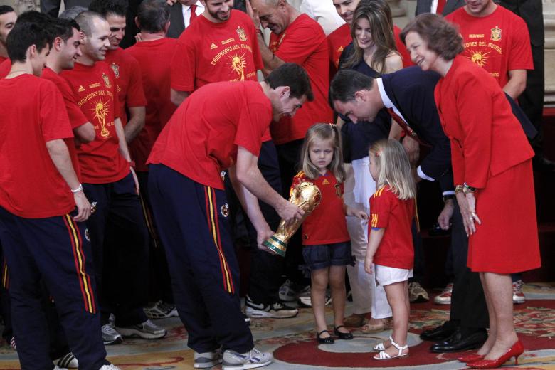 Spain's captain Iker Casillas, left, center shows the World Cup trophy to the daughters of Prince Felipe, third right, and Princess Letizia, fourth right, as Queen Sofia, right, looks on during a reception for the Spanish soccer team at the Royal Palace in Madrid on Tuesday, July 12, 2010