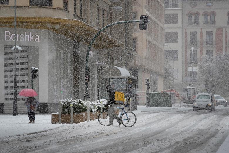 Un repartidor de comida a domicilio camina con su bicicleta por la calle Cortes de Navarra de Pamplona