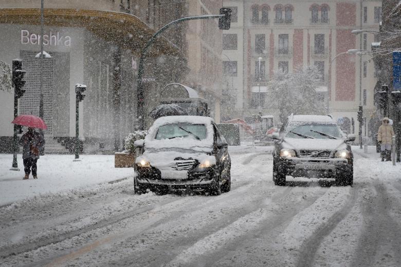 Dos coches circulan bajo una intensa nevada por la calle Cortes de Navarra de Pamplona donde el temporal de nieve ha llegado de lleno este fin de semana