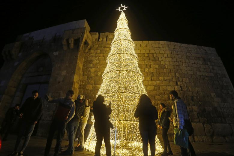Un grupo de sirios se reúne en torno a un árbol de Navidad en la capital Damasco