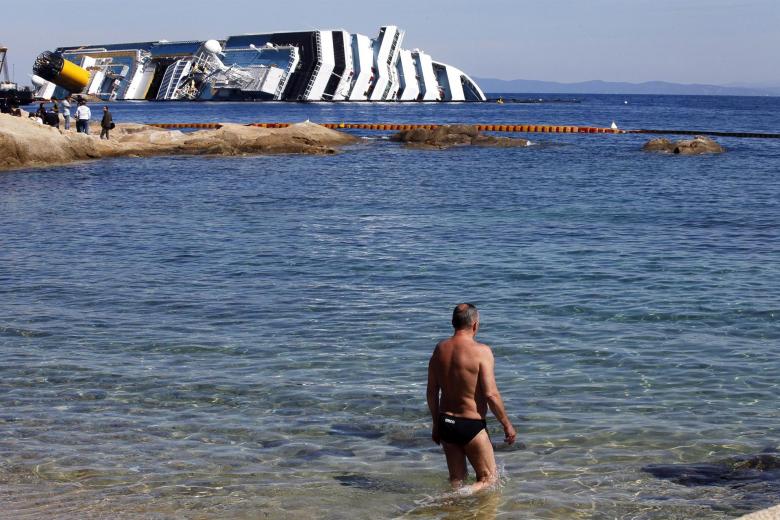 Un turista observa los restos del Costa Concordia en la isla de Giglio