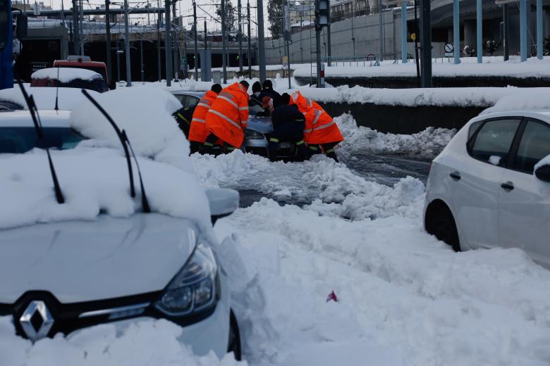 Los bomberos intentando sacar un automóvil atrapado en la nieve en Attiki odos, la carretera de circunvalación más grande de la capital griega