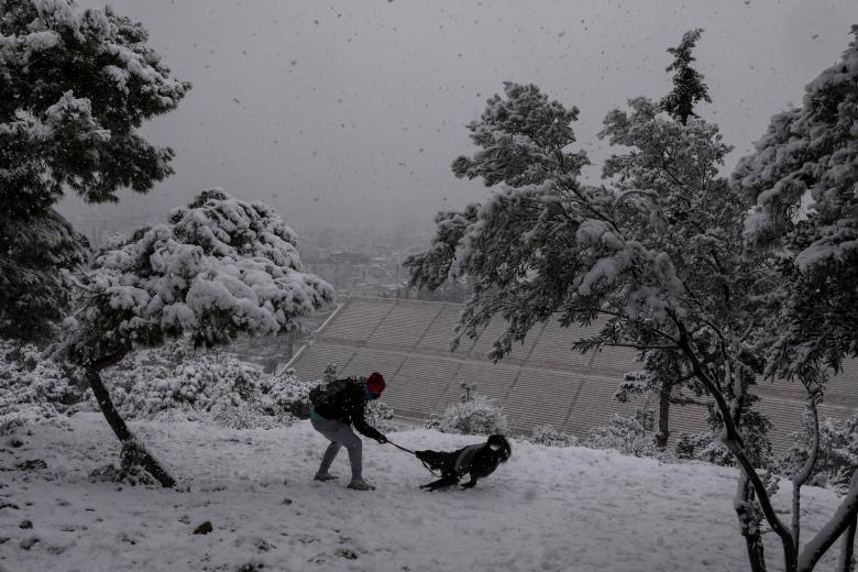 Un hombre juega con su perro en una colina cerca del Estadio Panatenaico de Atenas.