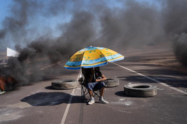 Un manifestante protesta entre barricadas, hoy, en Iquique (Chile). Bloqueo de carreteras, cierre de comercios y un paro de camioneros se desarrolló este lunes en la ciudad de Iquique, en el norte de Chile, en contra del aumento de la delincuencia y la crisis de migración irregular que hace meses afecta a la zona y sus alrededores