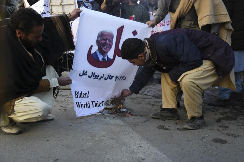 Un grupo de personas quema una pancarta con la imagen del presidente de Estados Unidos, Joe Biden, durante una protesta contra sus declaraciones de congelar los activos de Afganistán, en Kabul