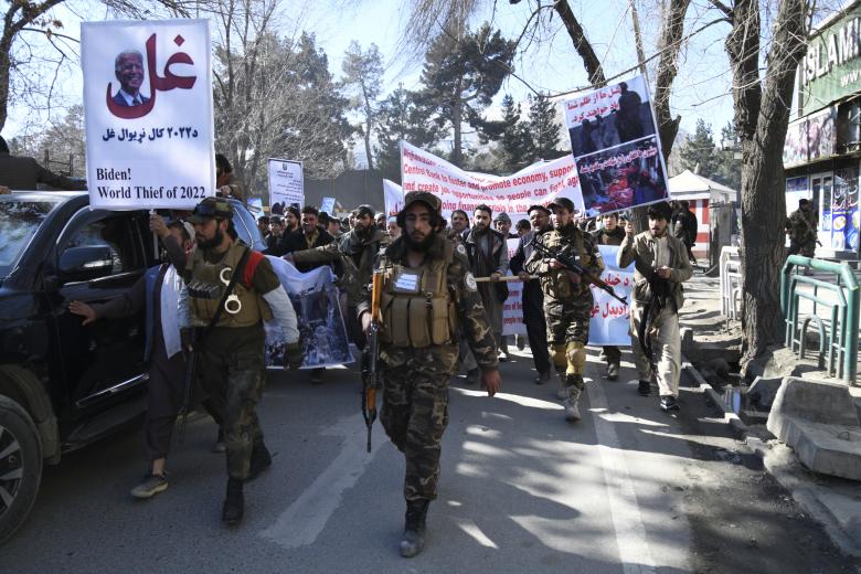 Un grupo de manifestantes sostienen pancartas mientras marchan durante una protesta contra las recientes declaraciones del presidente estadounidense Joe Biden de congelar los activos de Afganistán, en Kabul