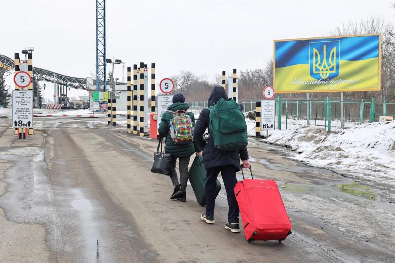 People carry their luggage in the Goptivka border crossing between Ukraine and Russia not far from Eastern Ukrainian city of Kharkiv, 16 February 2022 amid tensions on the Ukrainian-Russian border