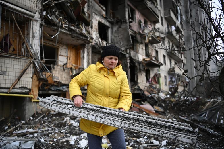 Una mujer recoge escombros de un edificio bombardeado en Kiev.