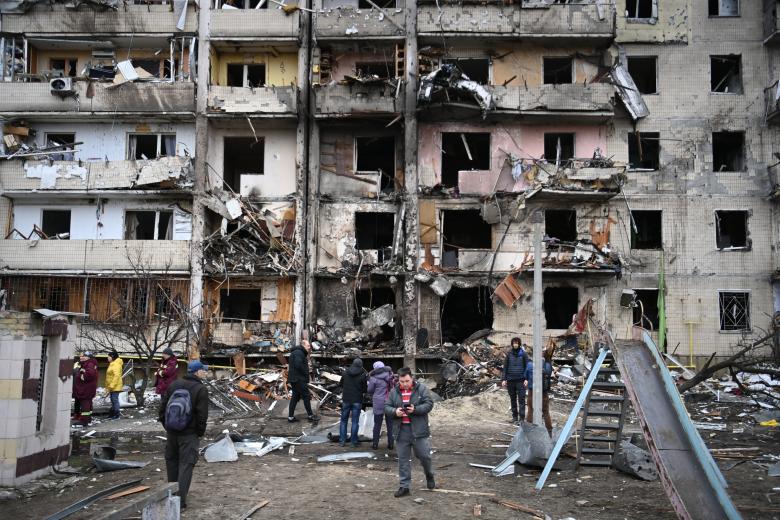 La gente se reúne frente a un edificio residencial dañado en la calle Koshytsa, un suburbio de la capital ucraniana, Kiev, donde supuestamente cayó un proyectil militar.
