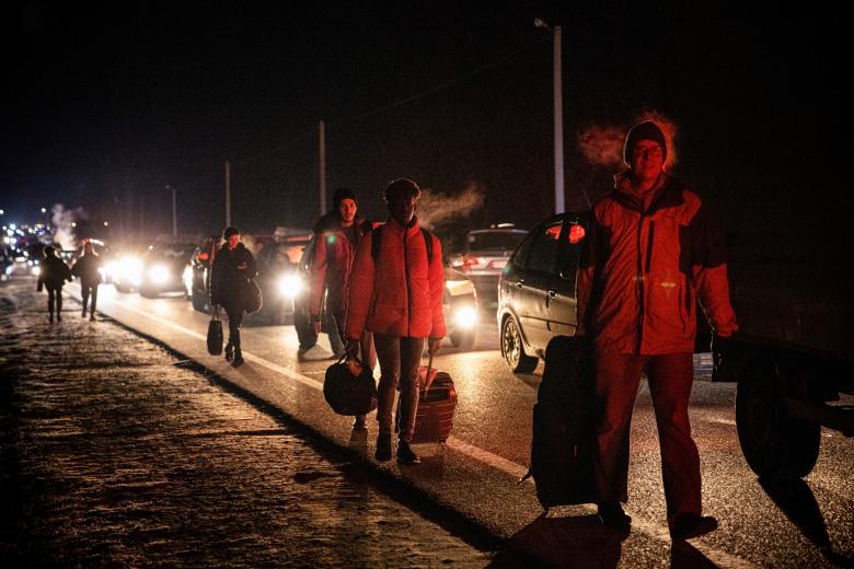 Personas a pie y en automóviles huyendo del país a Polonia por el cruce fronterizo de Korczowa-Krakovets en la madrugada de este sábado.