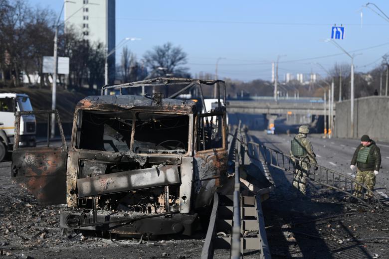 Soldados ucranianos pasan junto a un vehículo del ejército ucraniano quemado en el lado oeste de la capital ucraniana de Kiev.