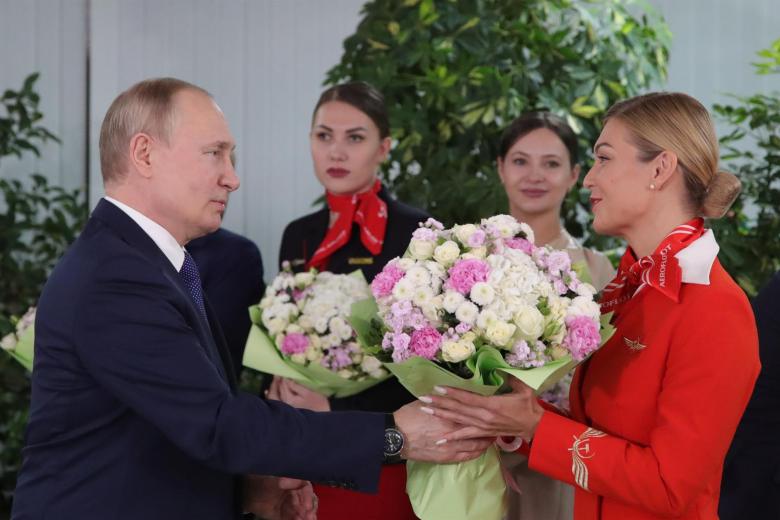 El presidente ruso Vladimir Putin (L) da flores a las mujeres de la tripulación de vuelo de las aerolíneas rusas durante su visita al centro de formación de aviación de PJSC Aeroflot