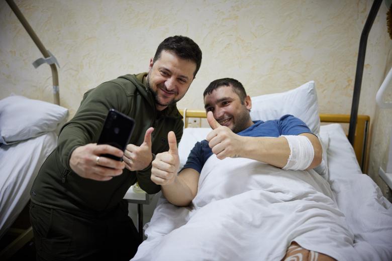 In this handout picture released and taken by Ukrainian Presidency Press Office on March 13, 2022, Ukrainian President Volodymyr Zelensky (2ndR) speaks to an injured man laying on a bed during a visit at a military hospital following fightings in the Kyiv region. - According to the presidency official website, Zelensky made a visit to the hospital to "award militaries with orders and medals for courage and dedication, and to honor the hospital staff for exemplary work in difficult conditions". (Photo by Handout / UKRAINIAN PRESIDENTIAL PRESS SERVICE / AFP) / RESTRICTED TO EDITORIAL USE - MANDATORY CREDIT "AFP PHOTO / UKRAINIAN PRESIDENTIAL PRESS SERVICE " - NO MARKETING - NO ADVERTISING CAMPAIGNS - DISTRIBUTED AS A SERVICE TO CLIENTS - RESTRICTED TO EDITORIAL USE - MANDATORY CREDIT "AFP PHOTO / Ukrainian presidential press service " - NO MARKETING - NO ADVERTISING CAMPAIGNS - DISTRIBUTED AS A SERVICE TO CLIENTS /