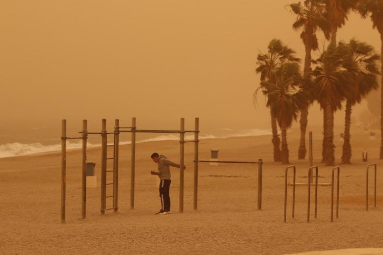 Un joven hace deporte en la playa de Aguadulce, Roquetas de Mar ( Almería) bajo la intensa calima debido al polvo procedente del desierto del Sáhara