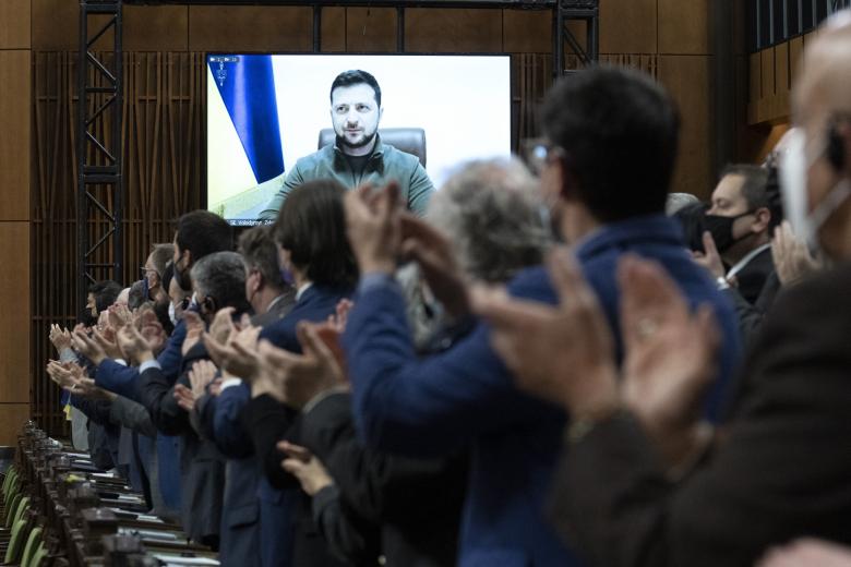 Canadian Members of Parliament and invited guests applaud Ukrainian President Volodymyr Zelensky before virtually addressing the Canadian Parliament, March 15, 2022 in Ottawa. (Photo by Adrian Wyld / POOL / AFP)