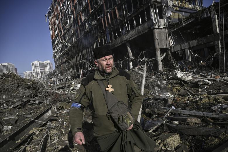 Un sacerdote ortodoxo busca posibles víctimas entre los escombros del centro comercial arrasado en Kiev