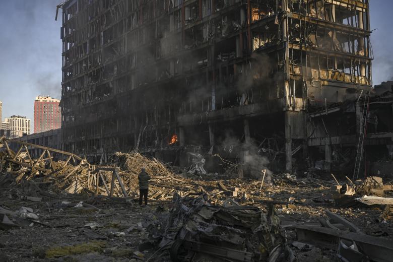 Un hombre mira el centro comercial Retroville en llamas y destruido después de un ataque ruso en el noroeste de la capital, Kiev.