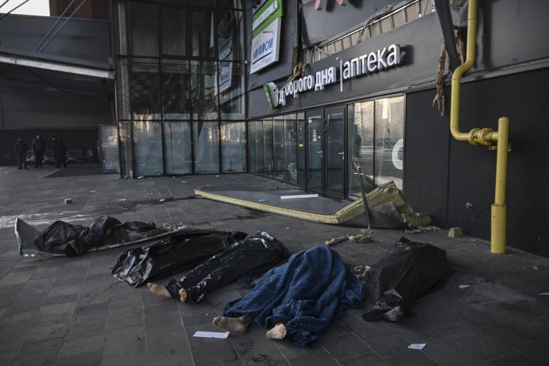 Los cuerpos de los militares ucranianos están cubiertos con mantas y bolsas de plástico fuera del centro comercial Retroville tras un ataque con misiles rusos