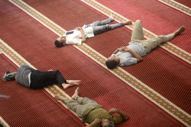 Cuatro personas descansan antes de romper el ayuno del Ramadán en la mezquita de Oman de Banda Aceh, Indonesia este miércoles
