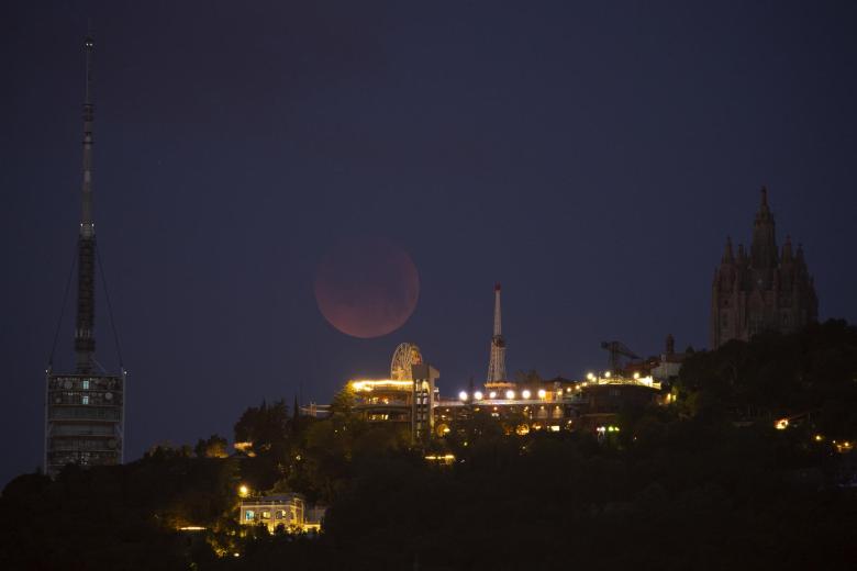 Vista del eclipse total de Luna tras el parque de atracciones del Tibidabo, la madrugada de este lunes