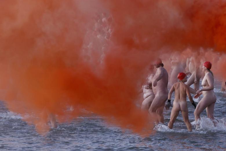 Nadadores entran en el agua, durante el baño nudista anual del solsticio de invierno dentro del festival Dark Mofo de Hobart en Long Beach, Tasmania, Australia, el 22 de junio de 2022