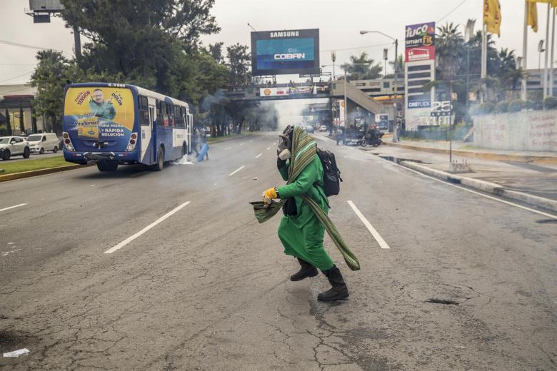 n hombre huye de los policías antimotines que disuelven con gases un bloqueo realizado por estudiantes universitarios, hoy en en Ciudad de Guatemala (Guatemala)