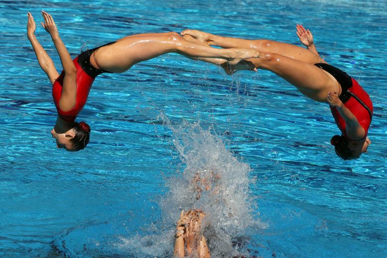 Dos integrantes de equipo español de natación sincronizada llevan a cabo una impresionante figura saltando sobre el agua